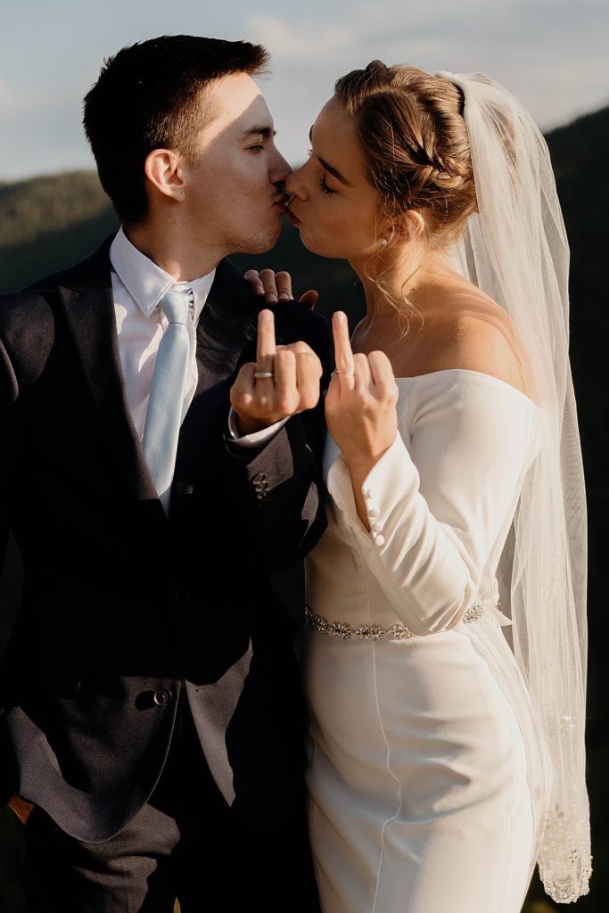 bride and groom kissing showing off their wedding rings
