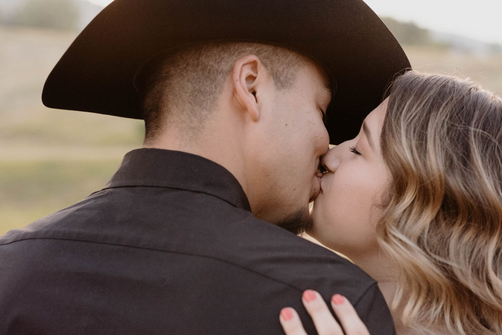couple kissing while wearing a cowboy hat