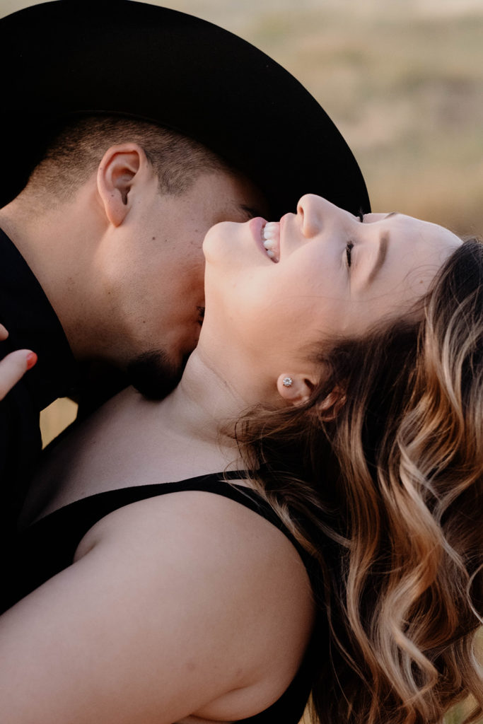 couple kissing neck at engagement session
