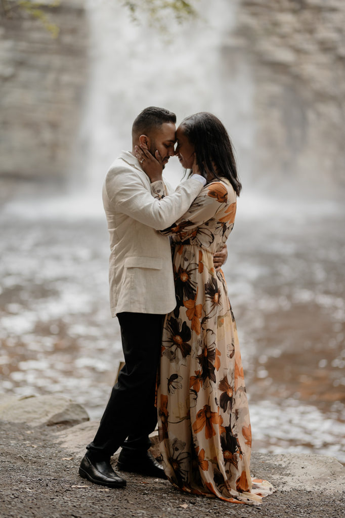 couple standing in front of waterfall at engagement photoshoot