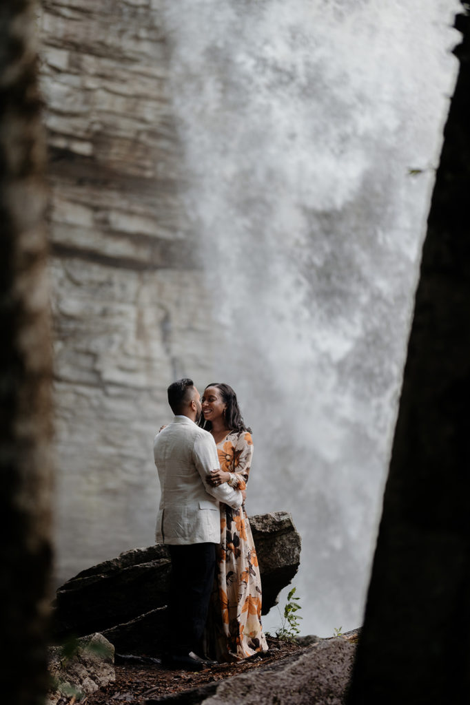couple standing in front of waterfall at engagement photoshoot